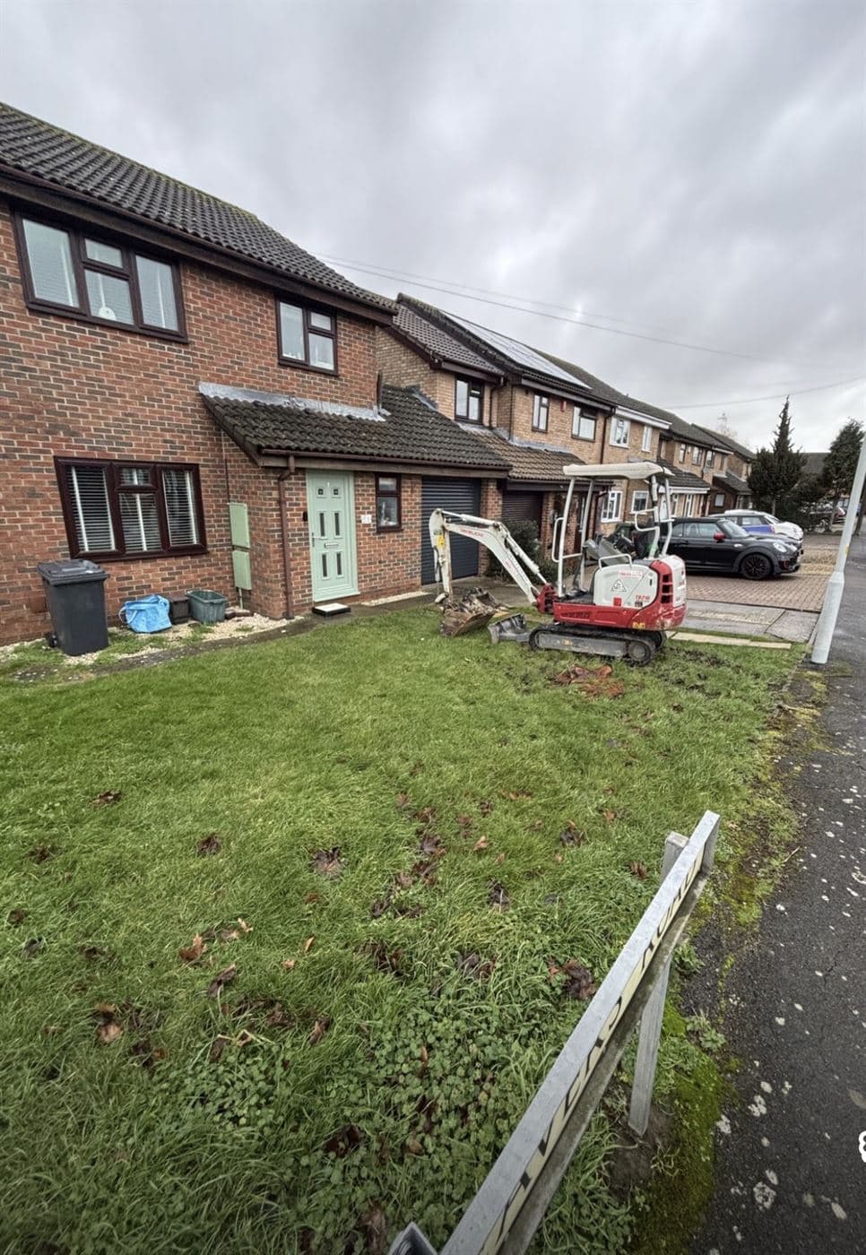 Mini digger excavating a front garden ready for a new driveway, Norwich